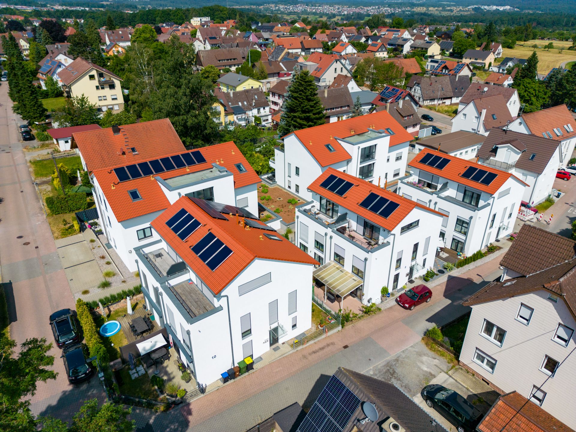 Mehrfamilienhaus mit weißen Wänden, roten Dächern und Solarzellen.