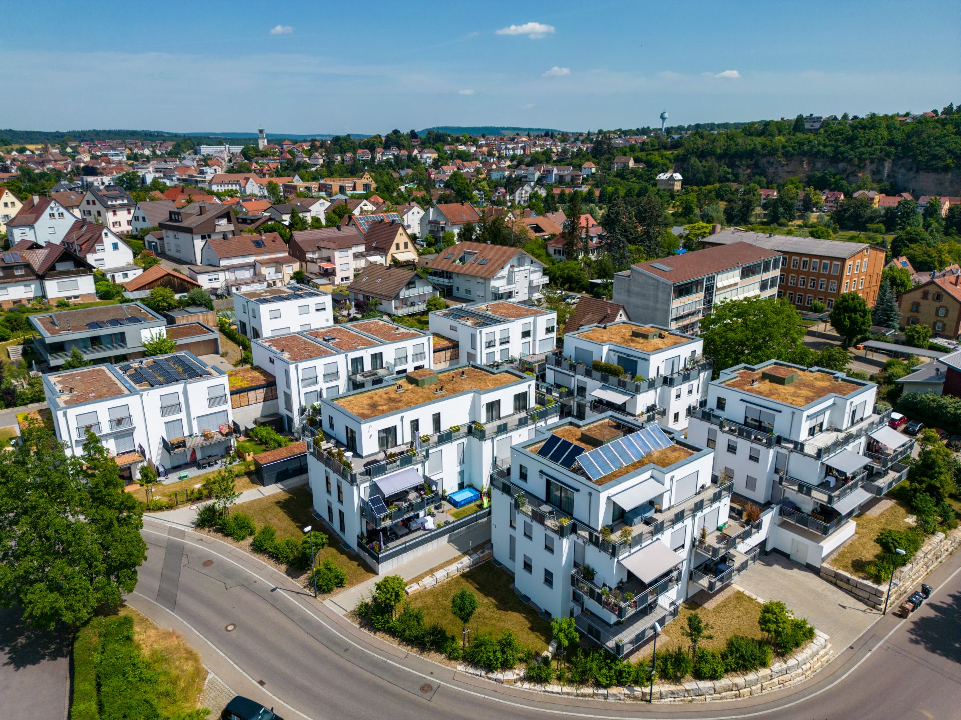 Modernes Wohnquartier mit weißen Gebäuden, Solarzellen und Grünflächen.